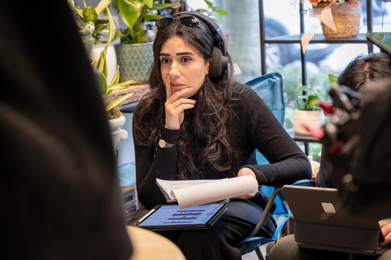 Mandana at the monitor with headphones, reviewing a take
