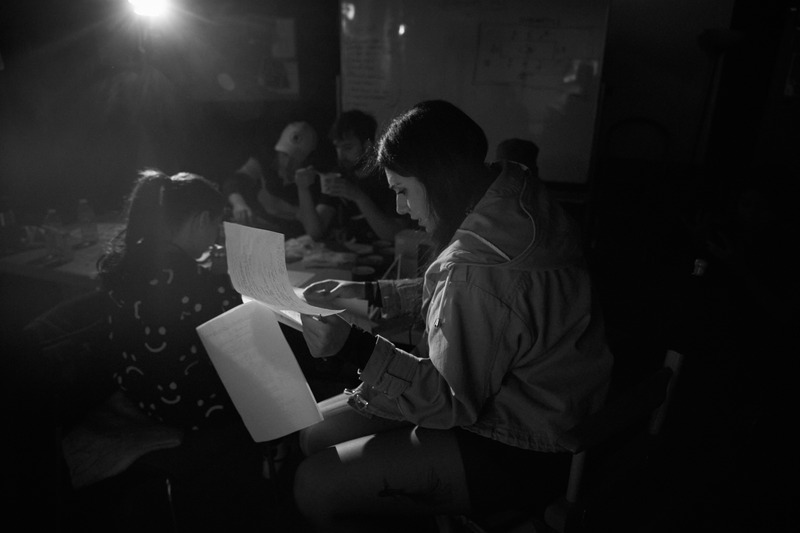 Black-and-white still of Mandana reading a script on set
